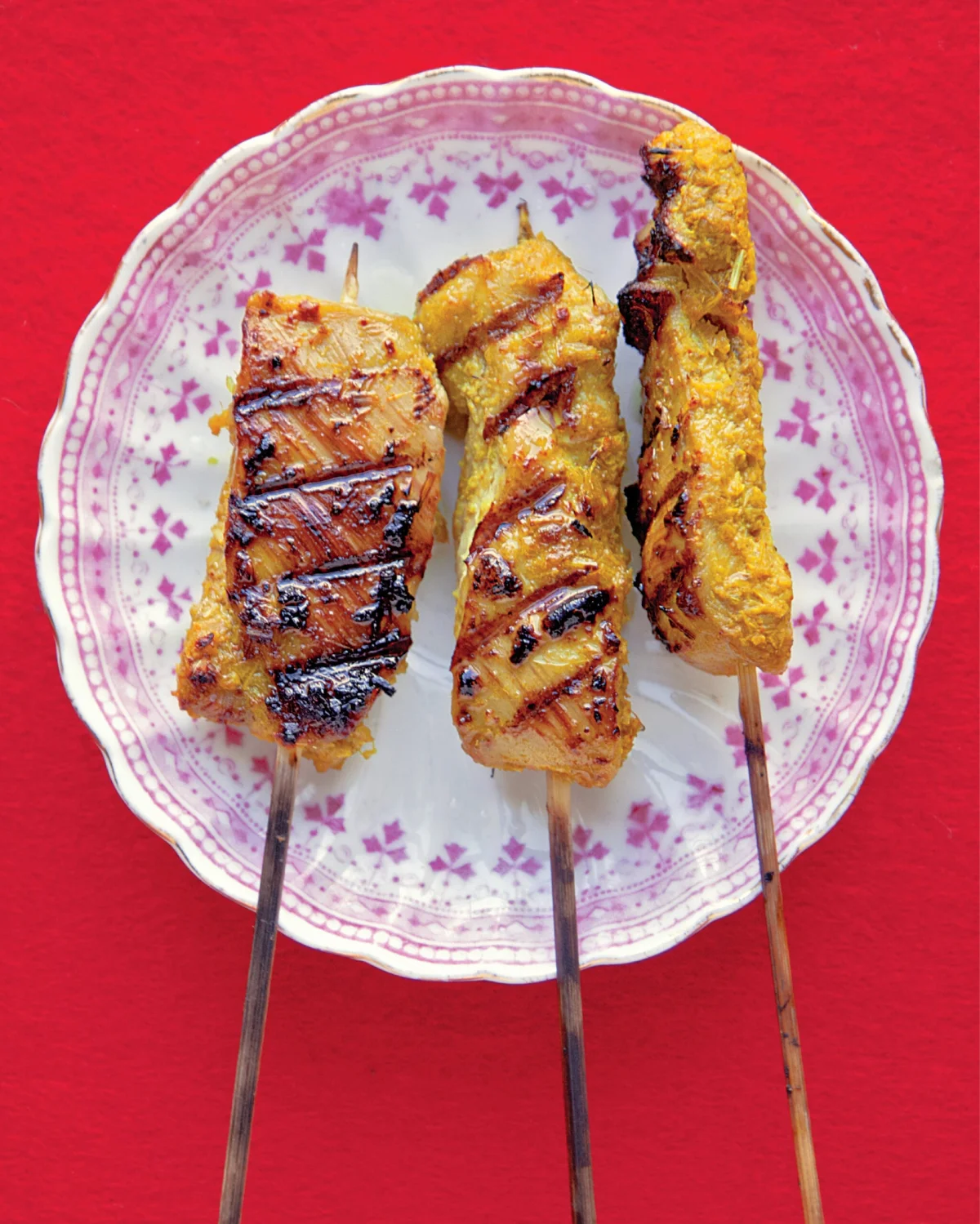 Three skewers of chicken satay on a plate