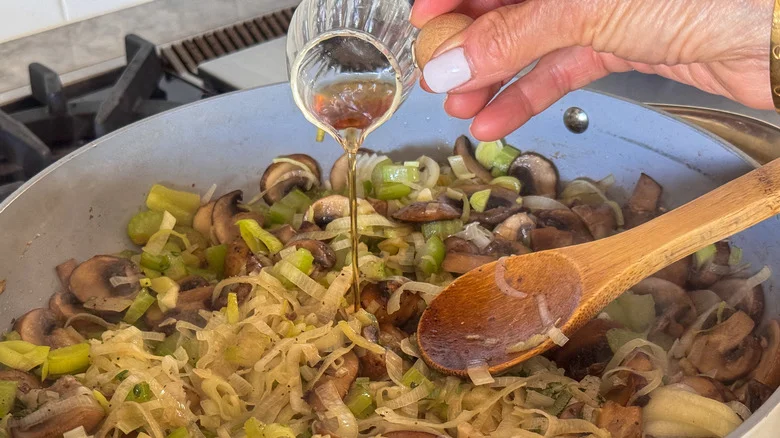 hand adding vinegar to pan