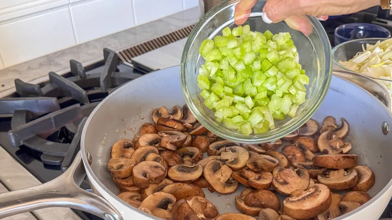 hand adding celery to pan