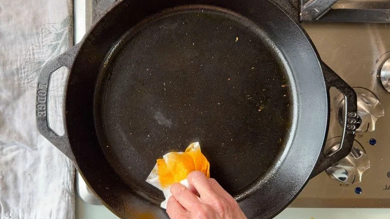 Wiping cast iron skillet clean with paper towel