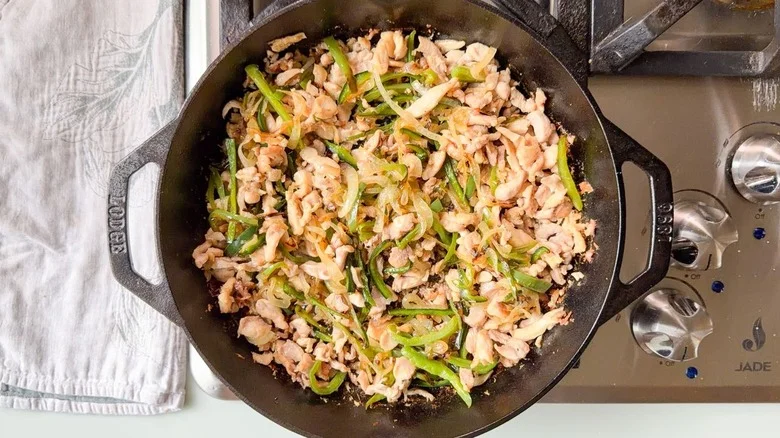 Sauteed chopped chicken thighs, poblano peppers, and sweet onions in cast iron skillet