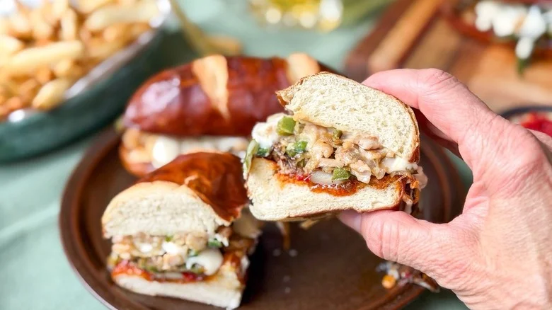 Holding half of a chicken cheesesteak to show the filling inside close up