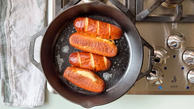 Pretzel hoagie buns toasting in cast iron skillet on stovetop