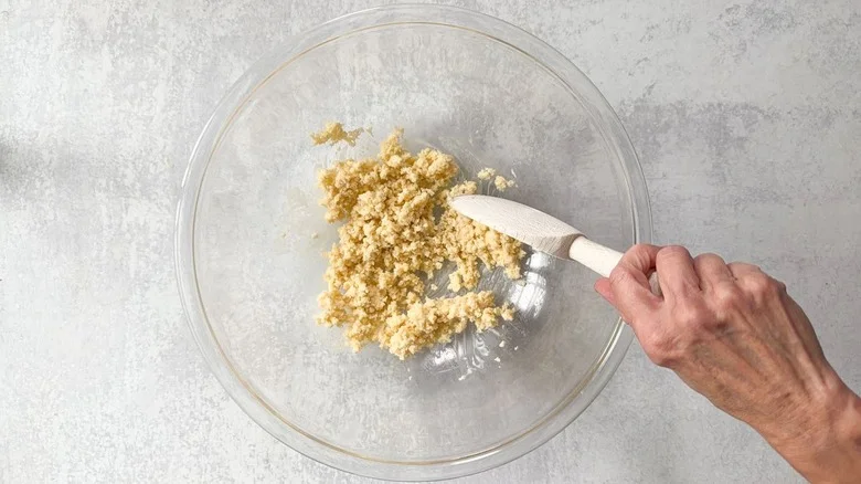 Mixing panko and heavy cream together in large glass bowl with wooden spoon