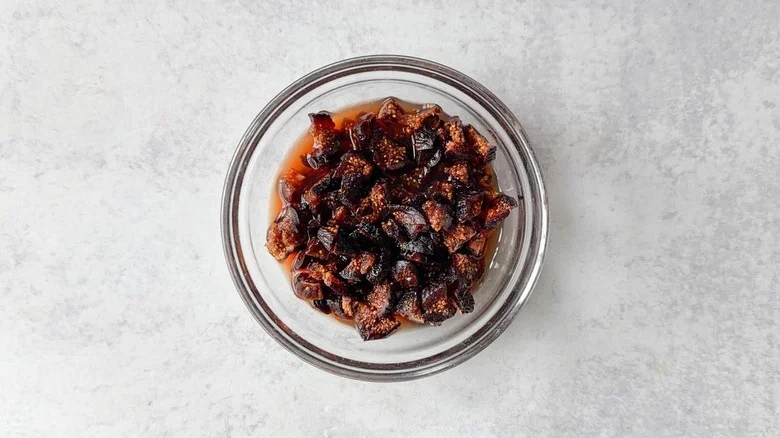 Quartered dried black mission figs soaking in port in glass bowl