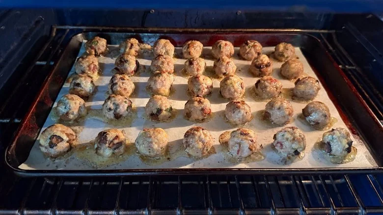 Fig and gorgonzola meatballs baking on parchment-lined baking sheet in oven