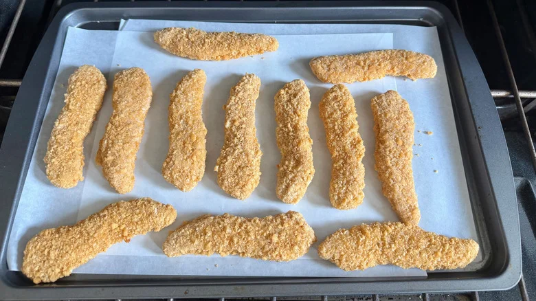 Breaded chicken strips on baking sheet