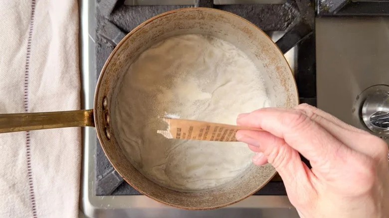 Sprinkling gelatin over soda in saucepan on stovetop