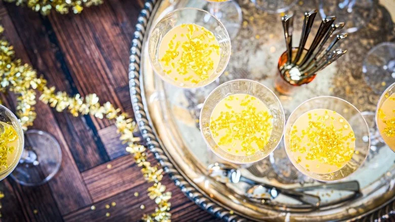 Champagne jell-o shots in mini flutes with spoons on silver tray with gold decor