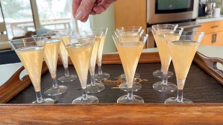 Sprinkling edible gold stars on top of champagne jell-o shots on tray