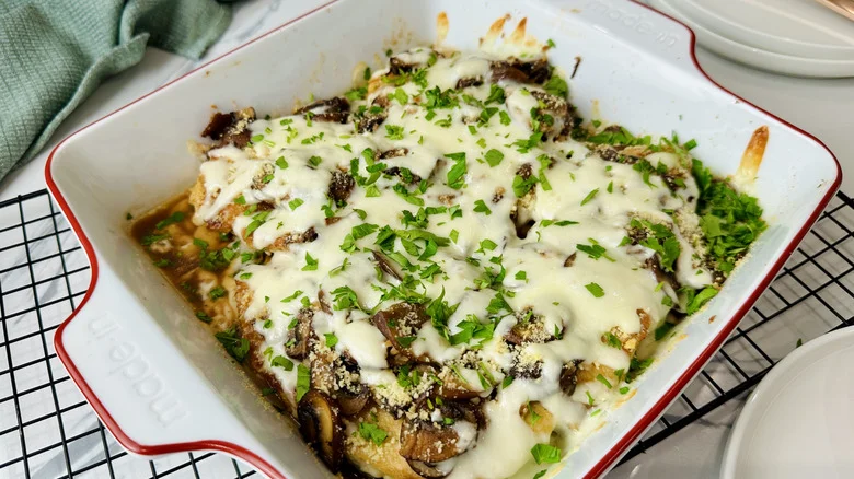 chicken with mushrooms, cheese, and parsley in a white pan