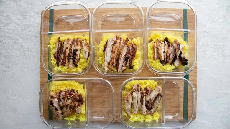five meal prep containers with sliced chicken and rice