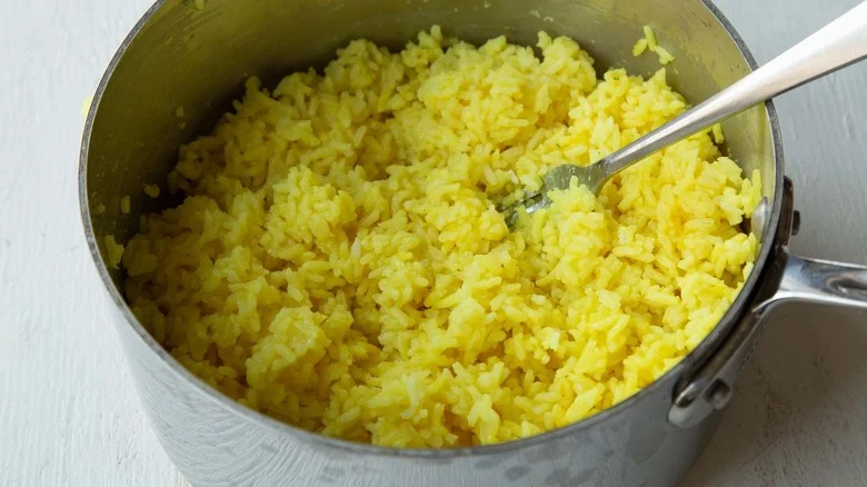 fluffing turmeric rice with fork