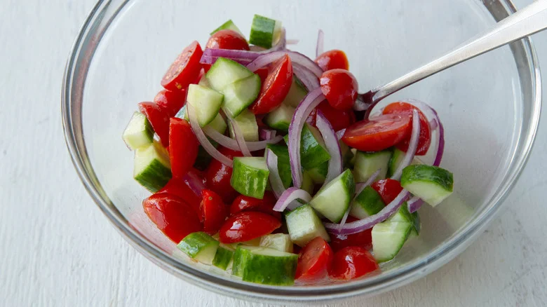 tomato, cucumber, onion in bowl with dressing