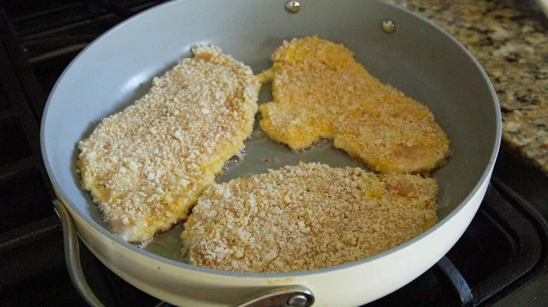 breaded chicken cutlets in a frying pan