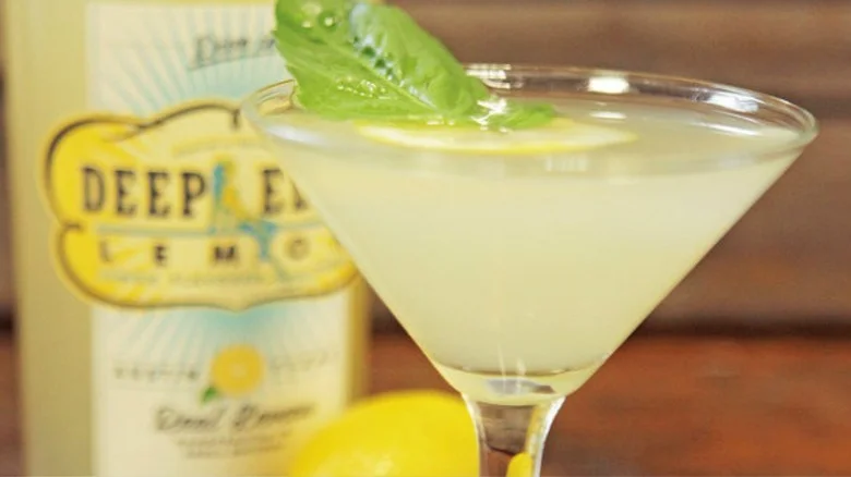 Lemon basil martini in a glass, garnished with lemon and a basil leaf