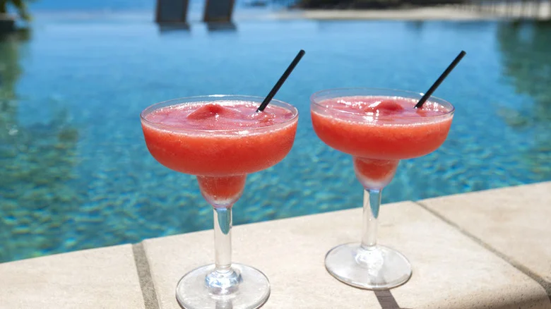 Two bright red strawberry daiquiris by the poolside