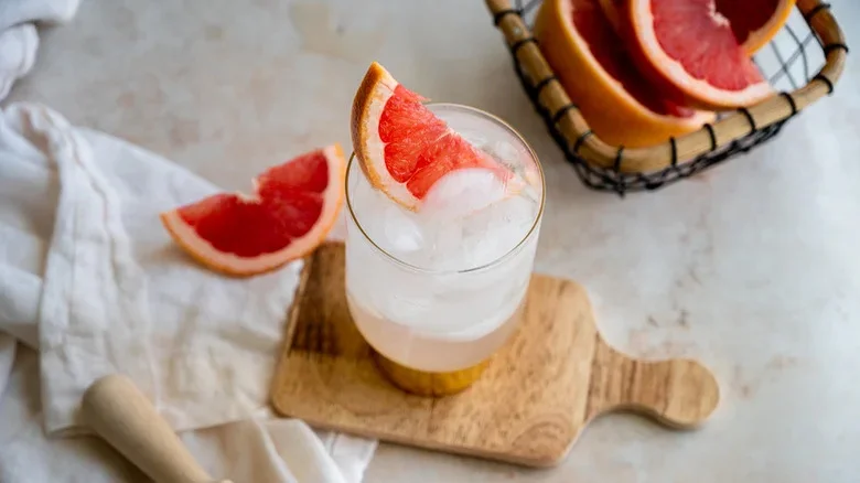 A sparkling paloma in a glass with ice and a pink grapefruit wedge