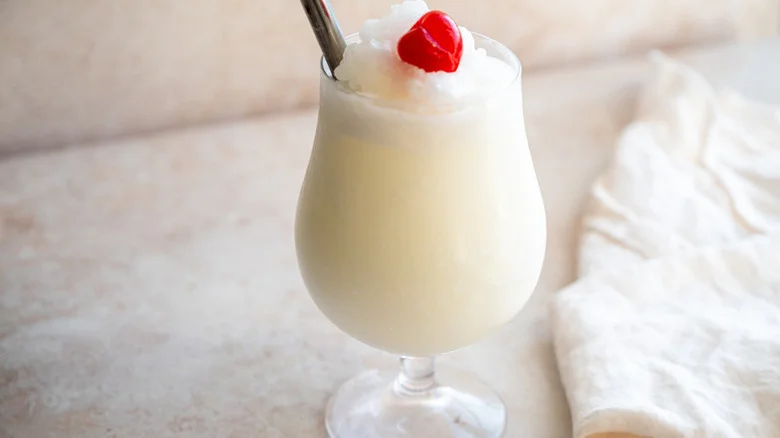 An off-white tropical frozen piña colada, garnished with a cherry
