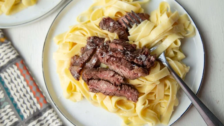 Steak Alfredo pasta on plate with fork