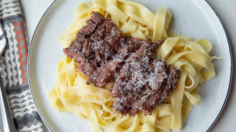 Alfredo pasta with sliced steak and Parmesan