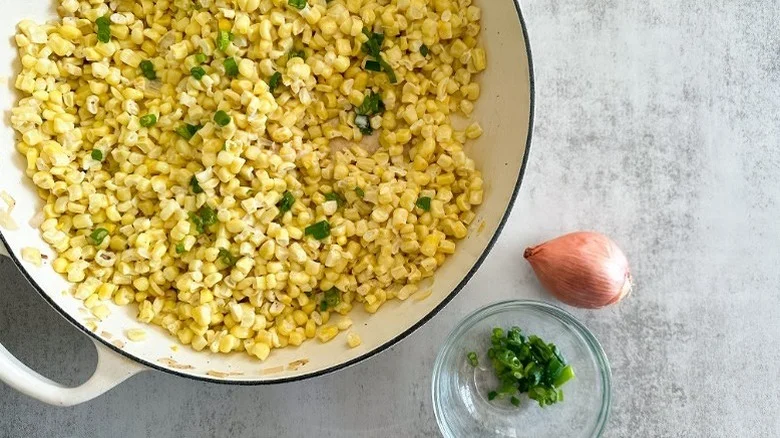 Pot of Easy Creamed Corn with whole shallot and green onions in ramekin