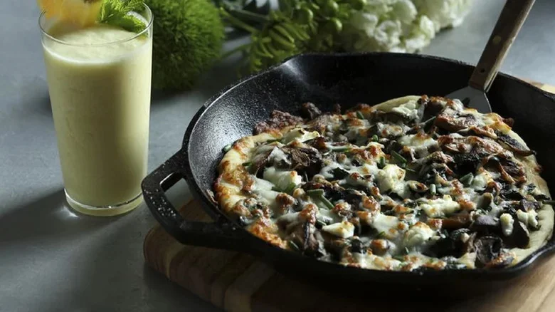 White Pizza With Mushrooms And Garlicky Greens in cast iron pan with a green smoothie