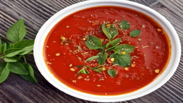 White bowl of Italian Tomato Sauce garnished with basil