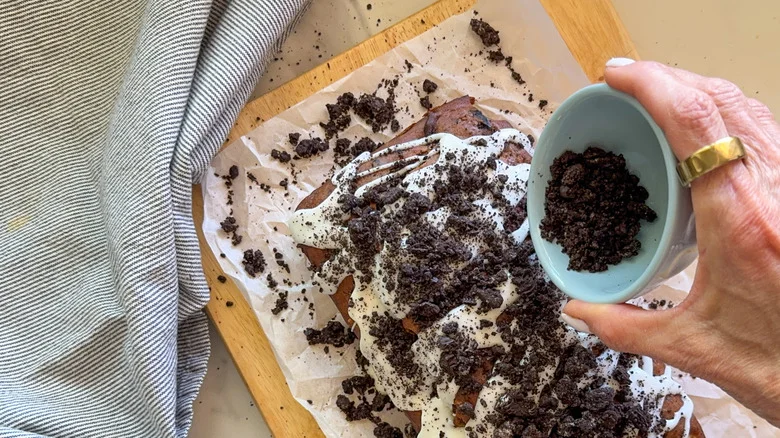oreo crumbs being poured onto banana bread