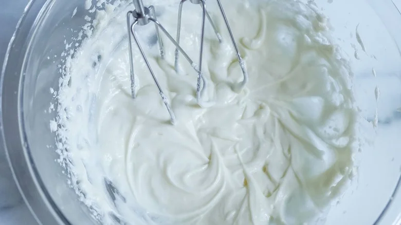 Beaten cream cheese in bowl with mixers
