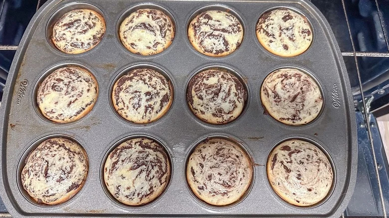 Cheesecake brookie muffins in muffin tin on oven rack