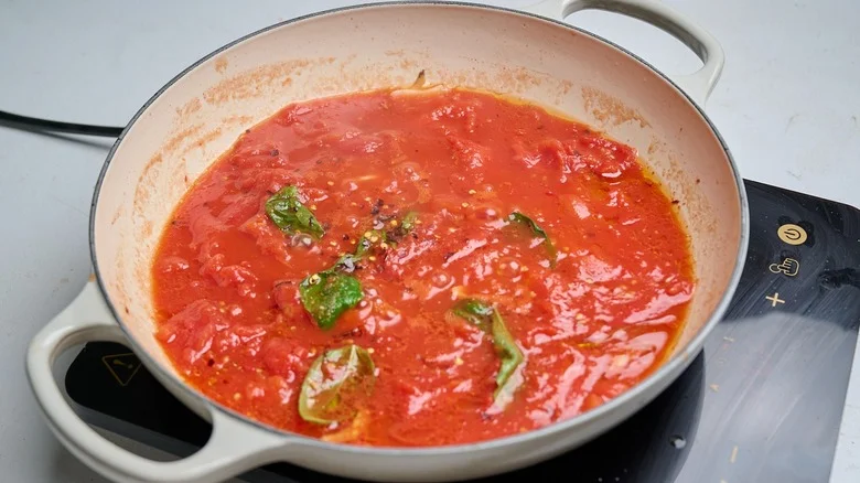 simmering tomatoes and basil in a skillet