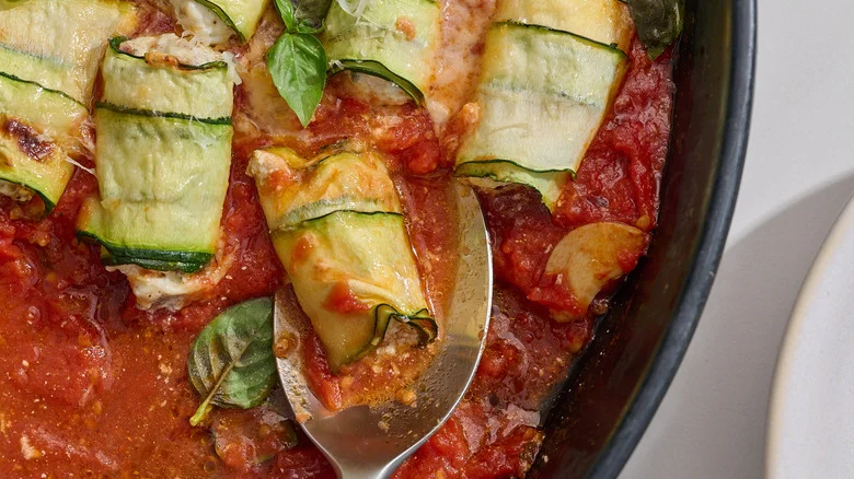 spoon scooping a zucchini involtini out of casserole dish