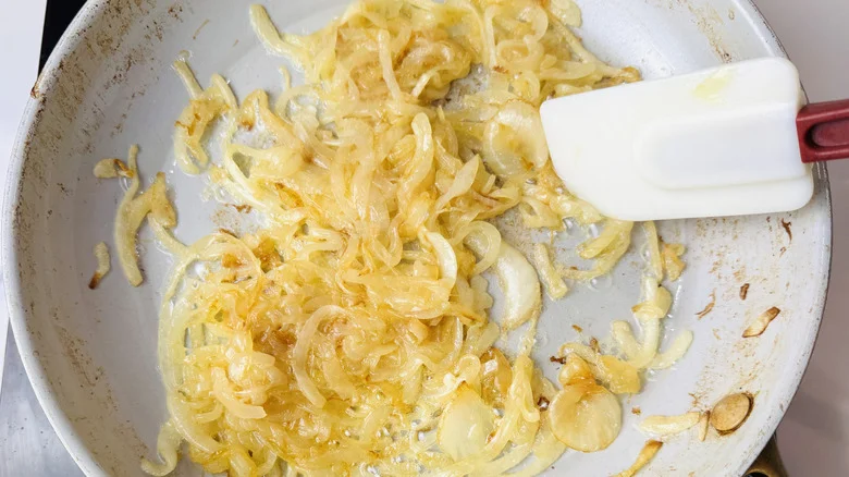 Sauteed onions and rubber spatula in pan
