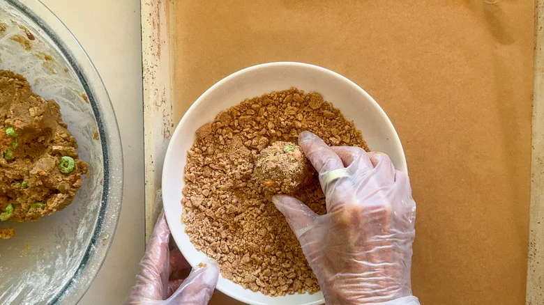 hands rolling dough in crumbs