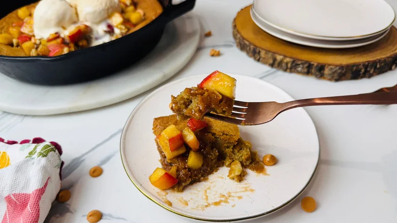 Serving of apple blondie on plate with fork holding bite in front