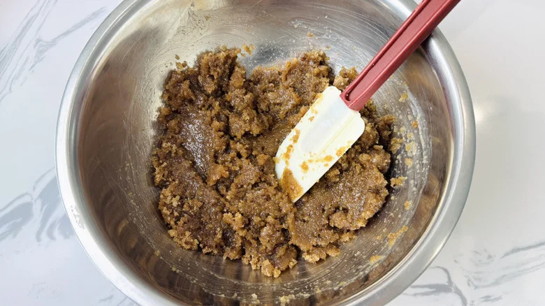 Butter and brown sugar mixture with rubber spatula in bowl
