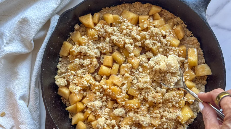 hand adding streusel to pan