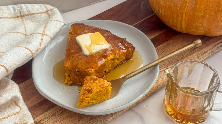 Slice of pumpkin cornbread with butter and honey on plate