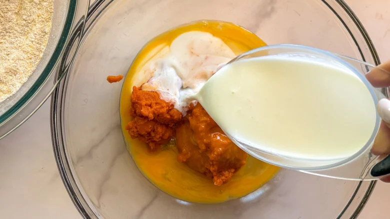 pouring milk into bowl with pumpkin puree