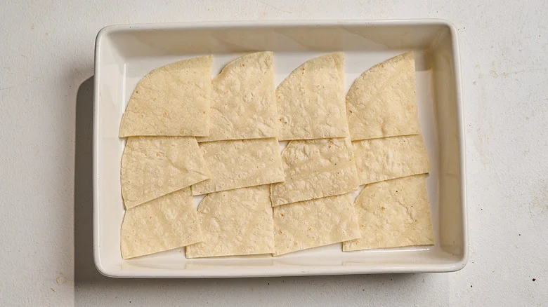 tortillas spread into a casserole dish
