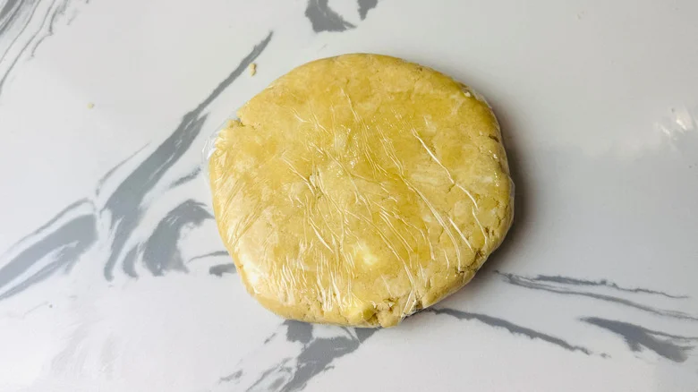 Plastic wrapped dough disc on countertop
