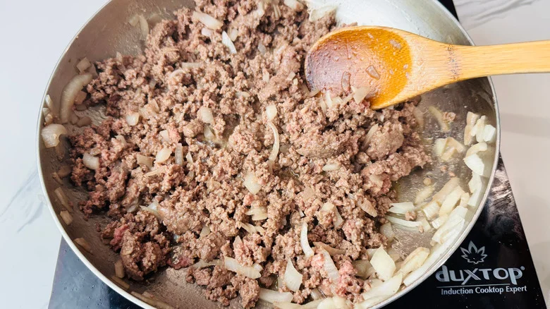 Beef and onions cooking in skillet