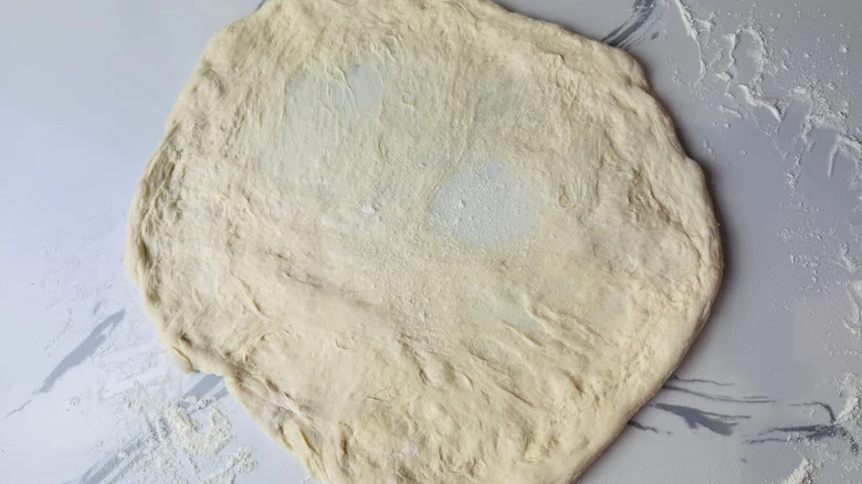 Stretched out pizza dough round on countertop