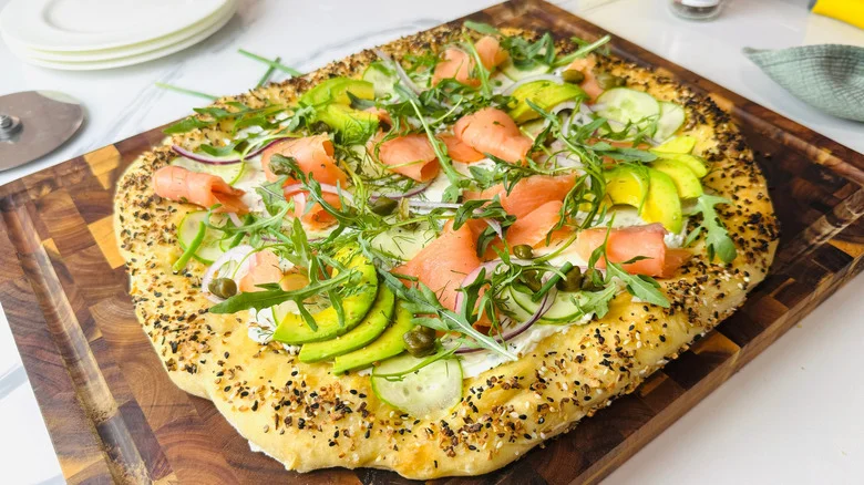 Bagels and lox inspired pizza on wooden board