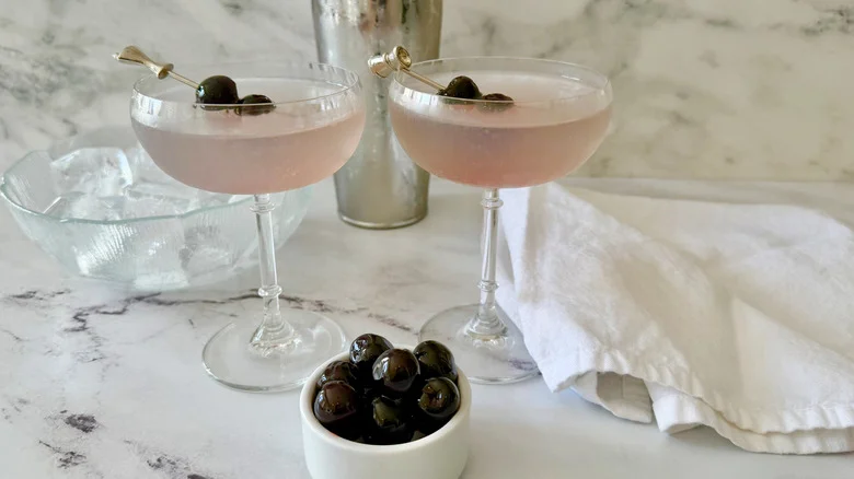 Aviation cocktails next to bowl of ice, napkin, and bowl of cherries