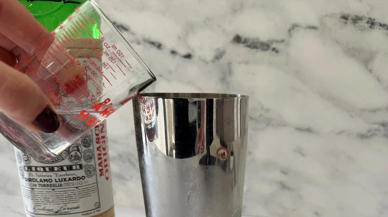 Hand pouring liqueur into cocktail shaker