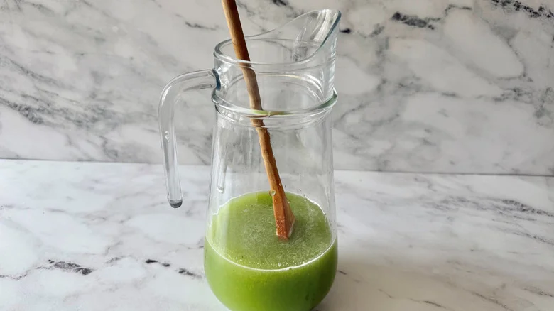 Pitcher with green liquid and wooden spoon