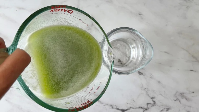 Cucumber juice pouring into pitcher
