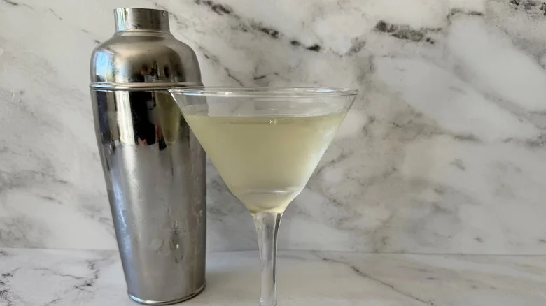 Martini in glass in front of cocktail shaker